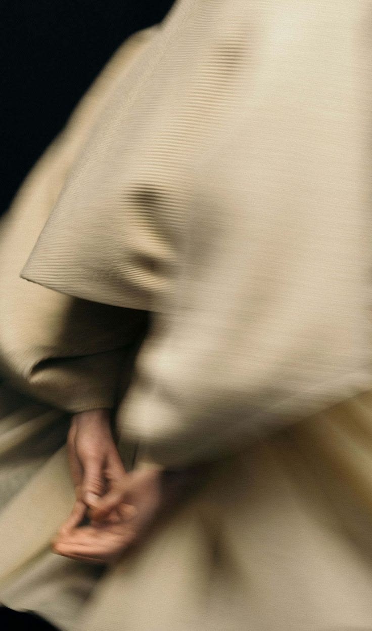 Hands folded over a draped cream sleeve