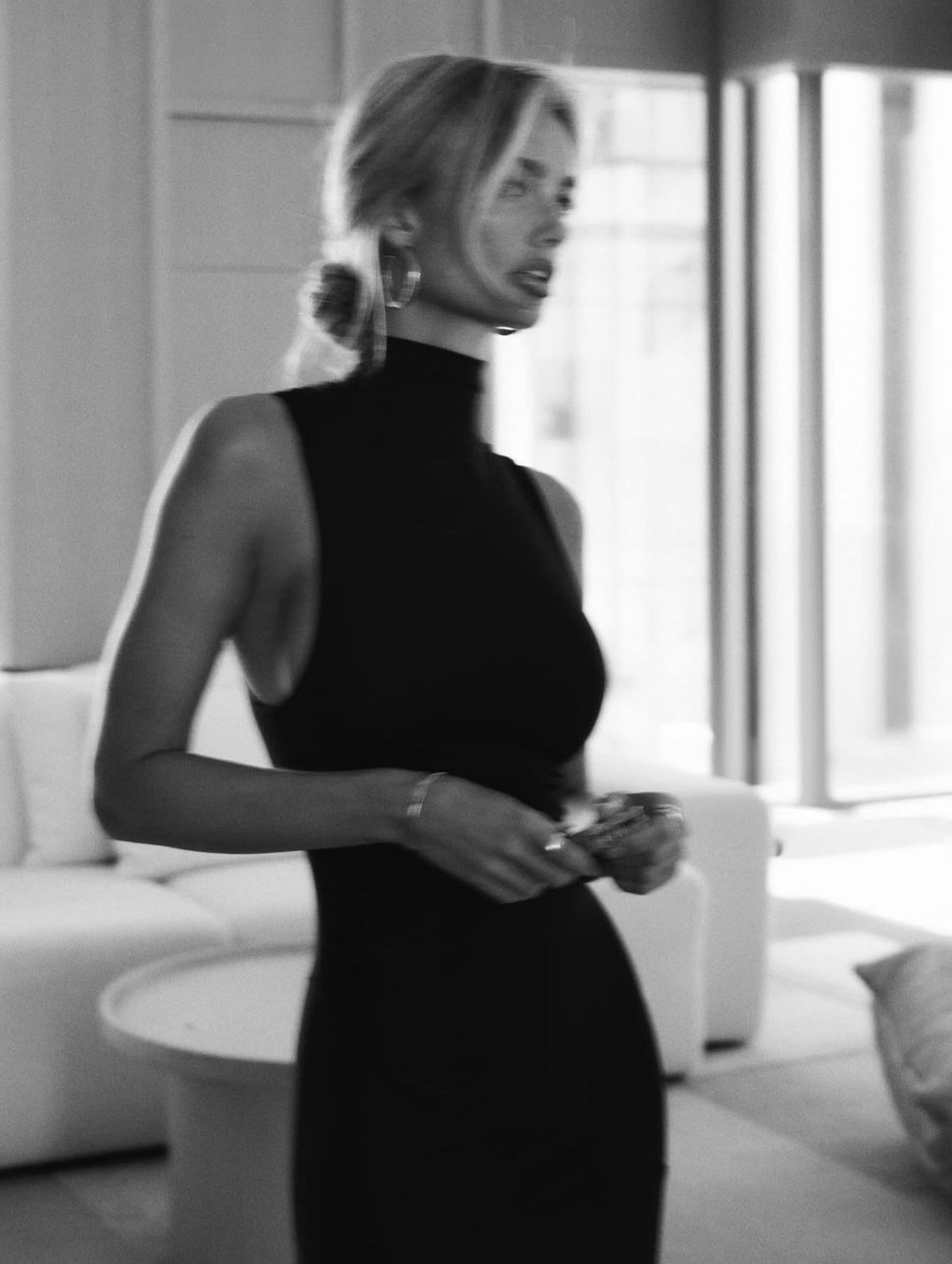 A woman in a black dress in a bright, softly blurred interior