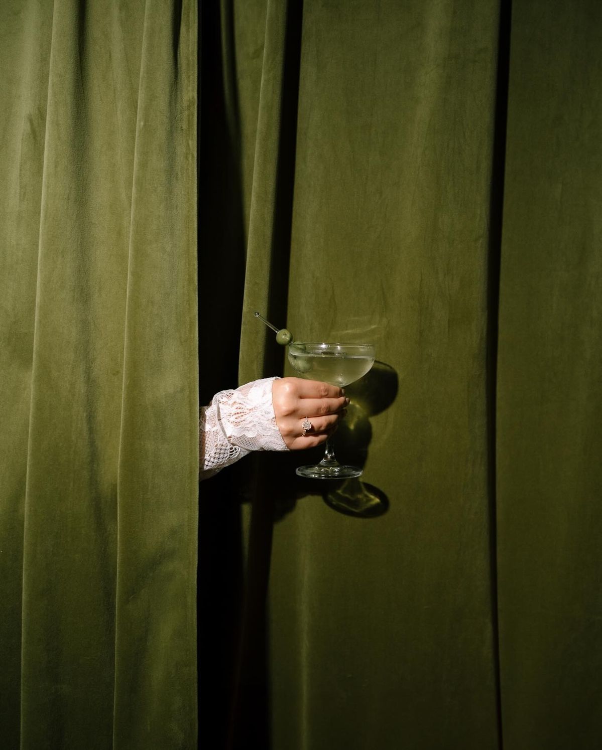 A glass held beside a deep green curtain
