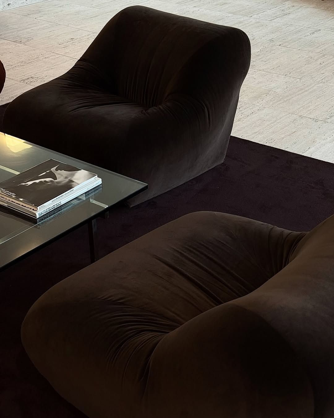 Dark velvet lounge chairs in a travertine interior
